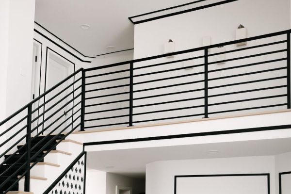 Modern staircase and upper landing with heavy black railings and trim, illustrating the overused black accent trend that designers are phasing out in favor of softer, warmer contrast.