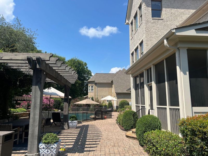 Charlotte luxury home exterior ready for spring after winter exterior painting planning Brick home exterior with screened porch, pergola, and landscaped backyard patio on a clear winter day