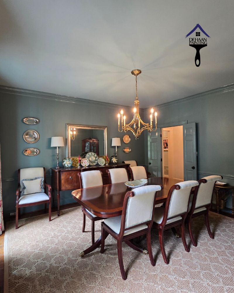 Why Professional Prep Shows Up in Your Estimate | Dining Room Painting Freshly painted dining room with gray-blue walls, crown molding, chandelier, and polished wood furniture showing a clean professional finish
